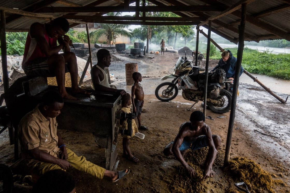 Waiting out a cloudburst while a team of young men press palm oil. 